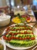 Teller mit Gurkenscheiben und Tomaten, im Hintergrund weiteres Buffet